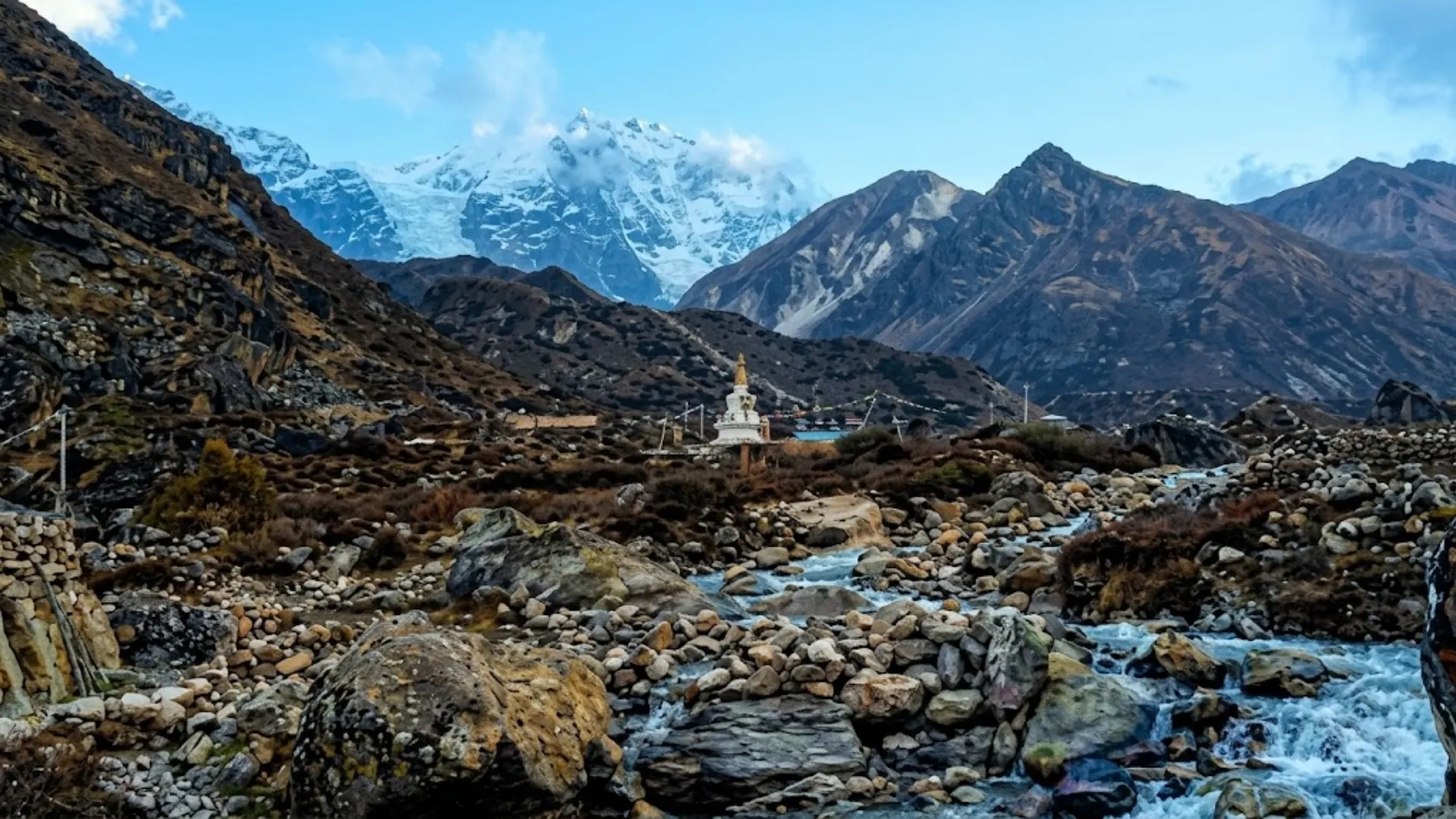 Panoramic view of snow-covered Mount Lhotse and Ama Dablam rising above alpine ridges under a clear blue sky.