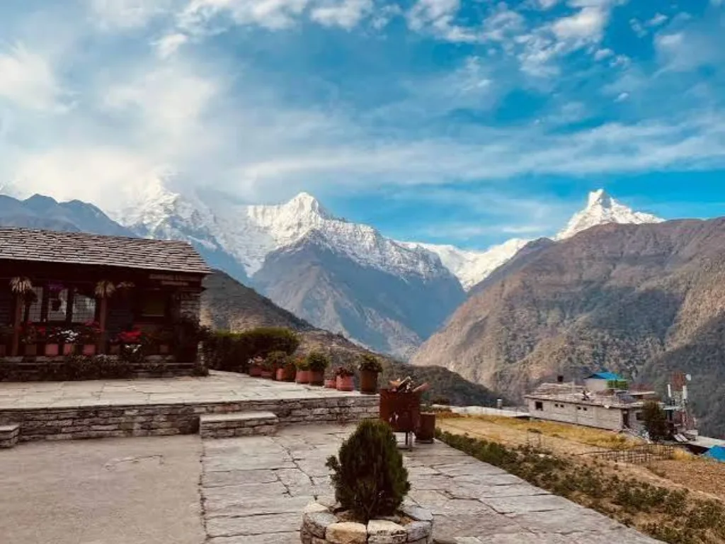 Stone mountain teahouse courtyard overlooking the snow-capped Annapurna South and Machapuchare peaks in Nepal.