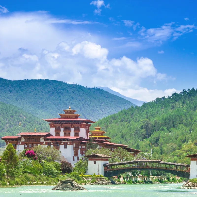 Historic Punakha Dzong fortress and traditional wooden cantilever bridge over the Mo Chhu river in Bhutan.