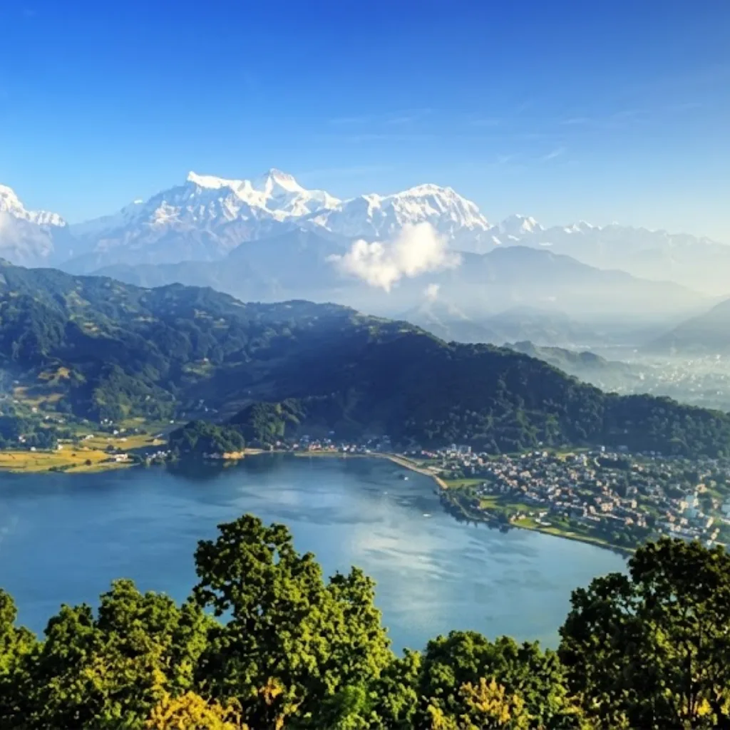 Deep blue waters of Begnas Lake surrounded by forested hills and snow-capped Himalayan summits in Nepal.